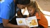 Eine Mitarbeiterin der australischen Lese-Stiftung Indigenous Literacy Foundation (ILF) liest ein Buch zusammen mit einem Kind.