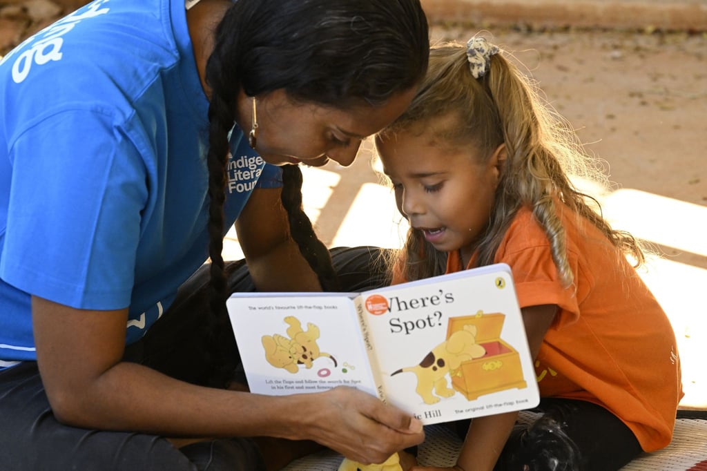 Eine Mitarbeiterin der australischen Lese-Stiftung Indigenous Literacy Foundation (ILF) liest ein Buch zusammen mit einem Kind.