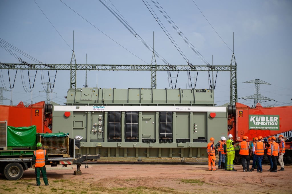 Techniker und Ingenieure stehen im Umspannwerk Wolmirstedt vor einem Transformator.