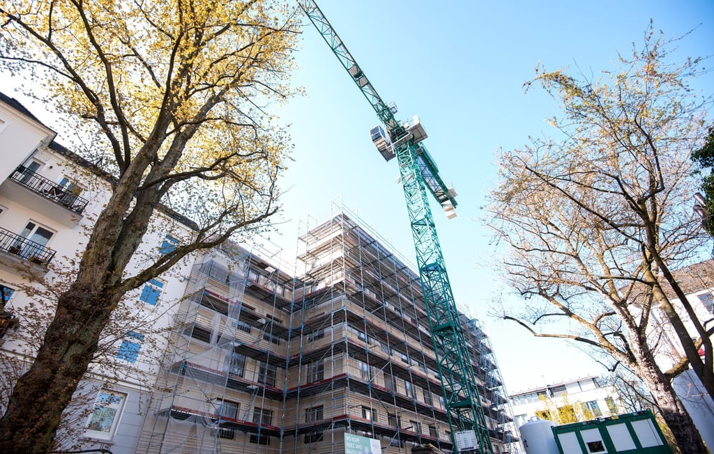 Ein Kran steht neben einem Neubau für ein Mehrfamilienhaus.