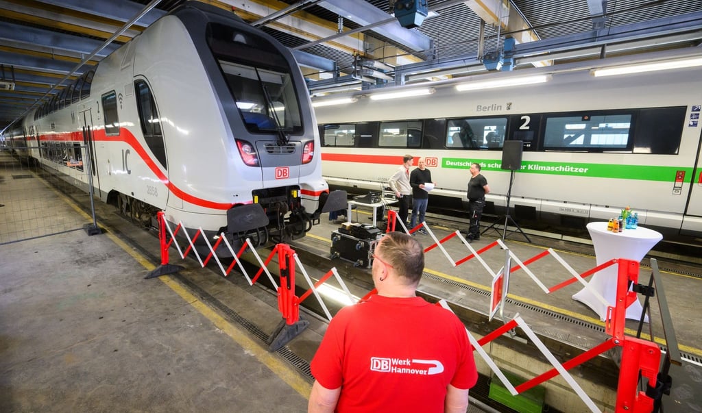 Ein Mitarbeiter der Deutschen Bahn steht im Werk Hannover neben einem IC2 Doppelstock Intercity und einem ICE T.