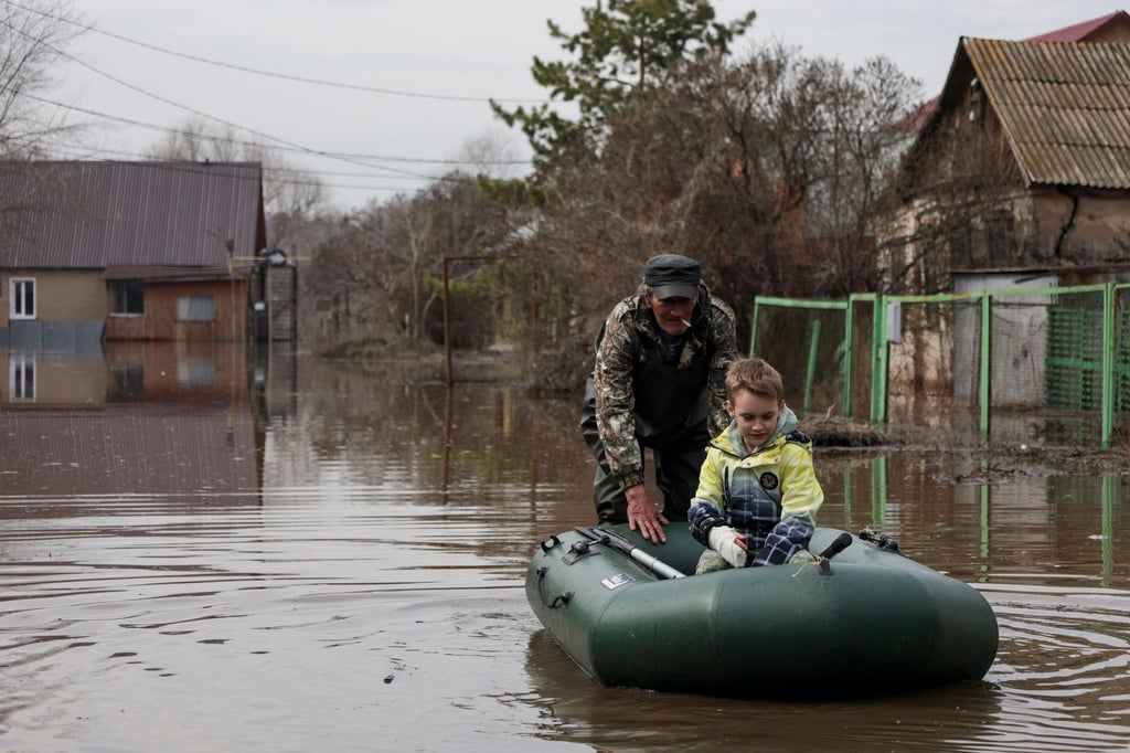 Ein Mann schiebt ein Schlauchboot mit einem Jungen in einem überfluteten Gebiet in Orenburg, Russland.