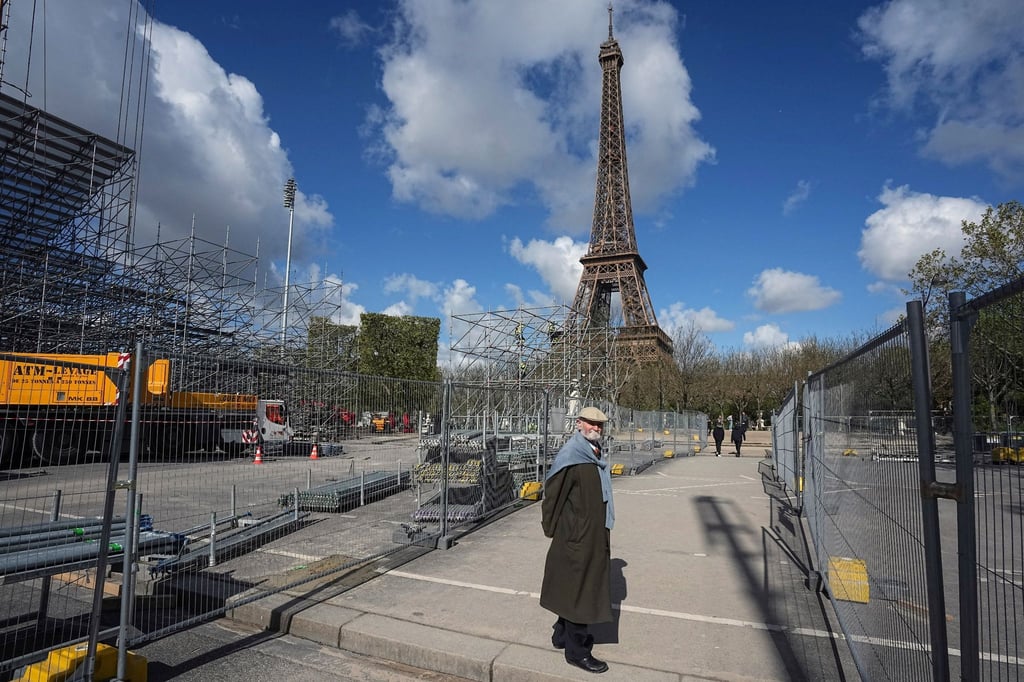 Ein Mann geht an einer Baustelle auf dem Champ-de-Mars in der Nähe des Eiffelturms im Vorfeld der Olympischen Spiele 2024 in Paris vorbei.