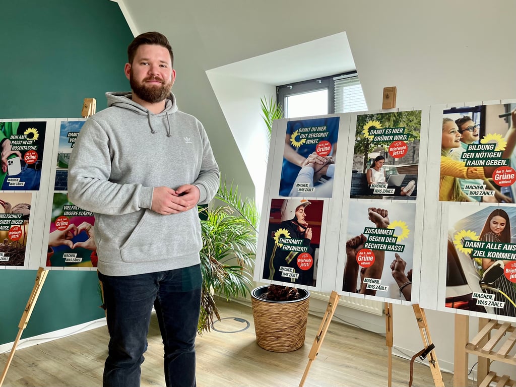 Grünen-Landeschef Dennis Helmich vor Plakaten für den beginnenden Kommunalwahlkampf.