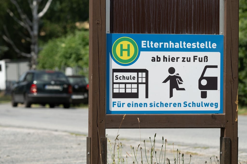 Ein Schild mit der Aufschrift „Elternhaltestelle“ steht auf einem Parkplatz.