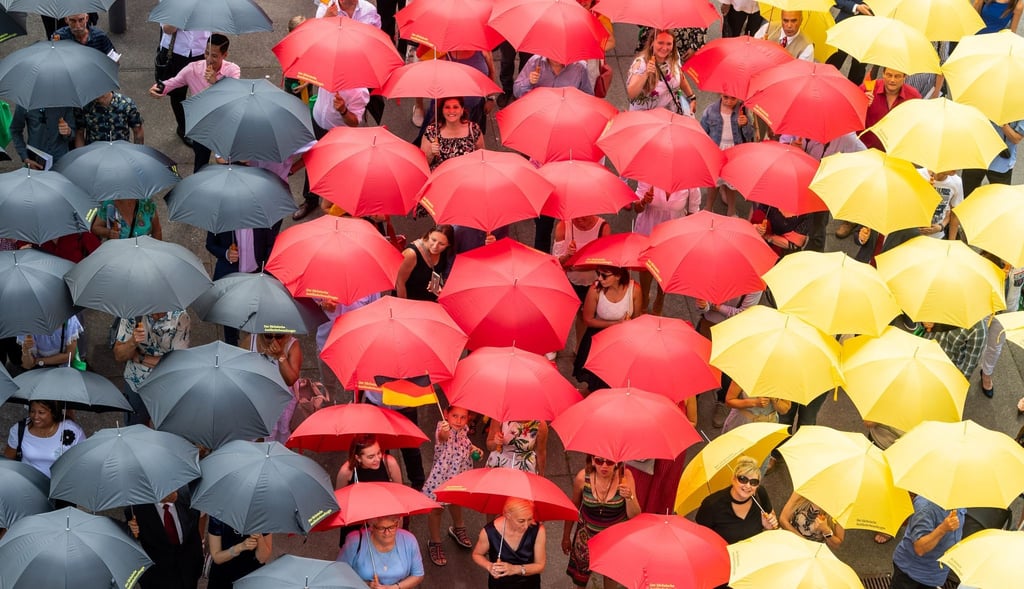 Eingebürgerte Menschen stehen mit schwarz-rot-goldenen Regenschirmen nach dem Einbürgerungsfest vor dem Sächsischen Landtag.
