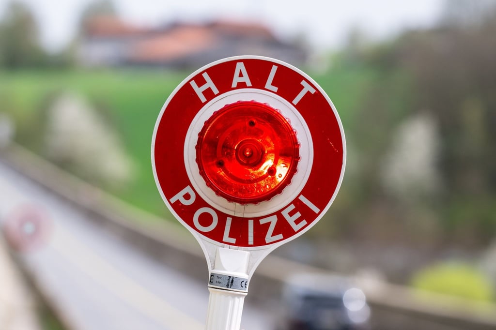 Eine Kelle mit der Aufschrift „Halt Polizei“ wird während einer Verkehrskontrolle hochgehalten.