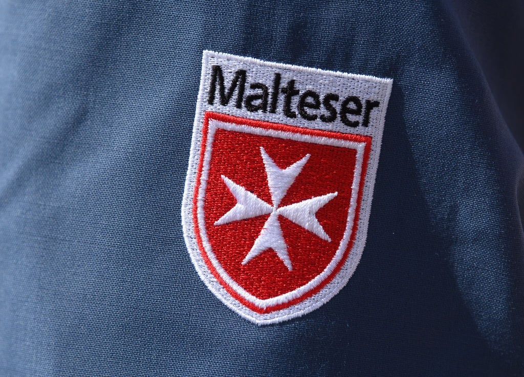 Das Logo der Malteser ist an der Jacke eines Helfers zu sehen.