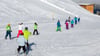 Bekanntes Bild aus den Skigebieten: Skischüler fahren in Reih und Glied die Piste ab.