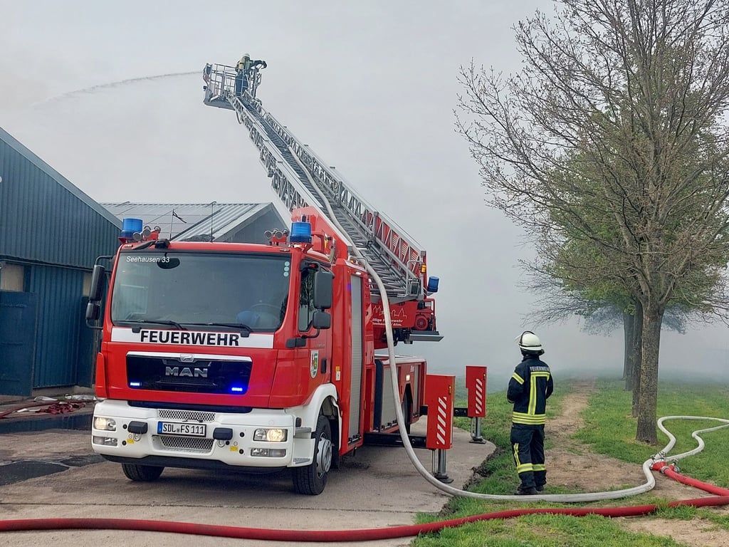 Einsatzkräfte der Feuerwehr versuchen in der Altmark im dichten Rauch den Brand in der einer Schweinemastanlage zu löschen.