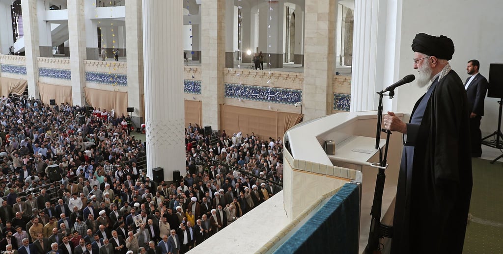 Ajatollah Ali Chamenei hält bei seiner Rede den Lauf eines Gewehrs in der Hand.