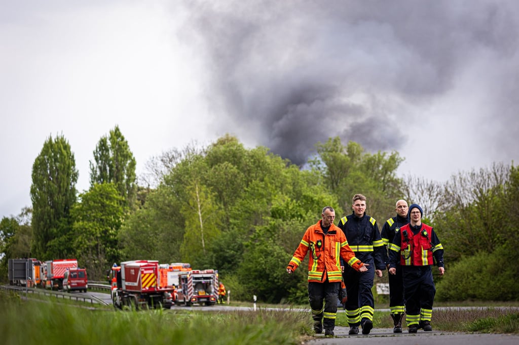 Einsatzkräfte und -fahrzeuge der Feuerwehr stehen bei einem Großbrand in einem Braunschweiger Industriegebiet.