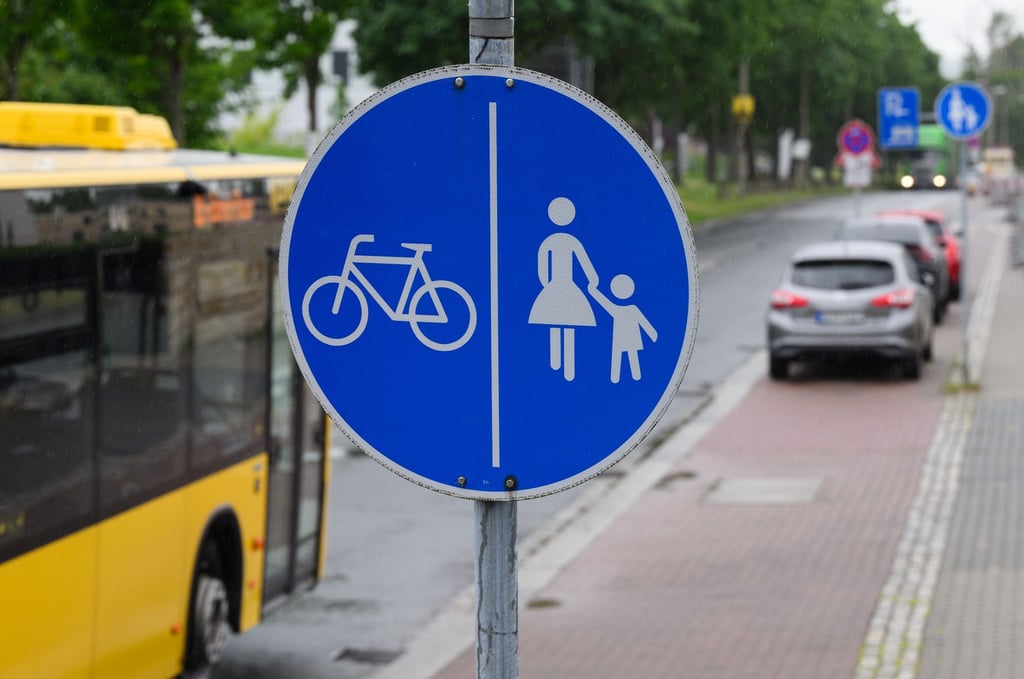 Ein Schild für einen getrennten Rad- und Gehweg steht vor einer Zone, in der das Parken auf halbem Gehweg erlaubt ist.