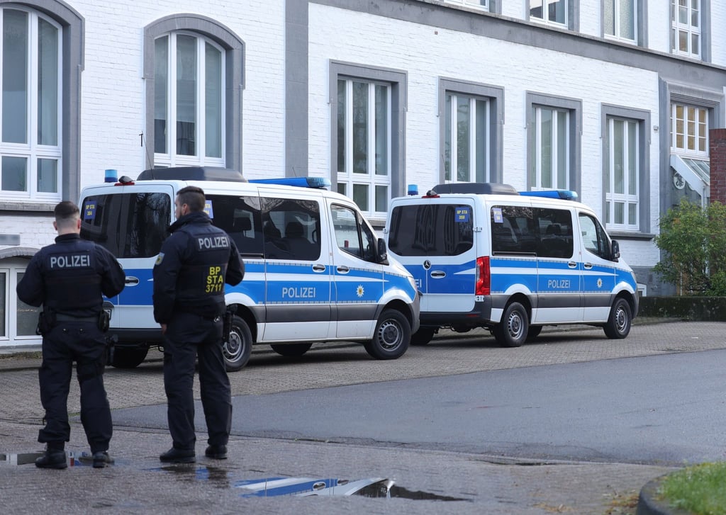 Polizisten stehen vor einem Gebäude, das durchsucht wird.