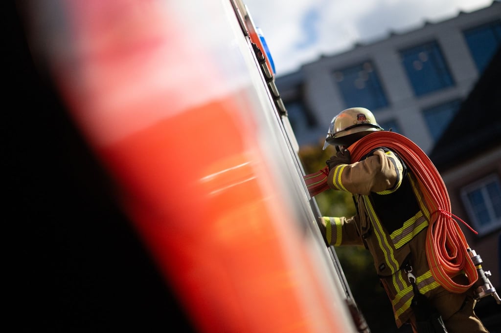 Eine Einsatzkraft der Feuerwehr nimmt während eines Pressetermins einen Schlauch aus einem Einsatzfahrzeug.