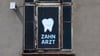 Zahnarzt steht an einem Fenster eines Hauses, in dem sich eine Zahnarztpraxis befindet, geschrieben.
