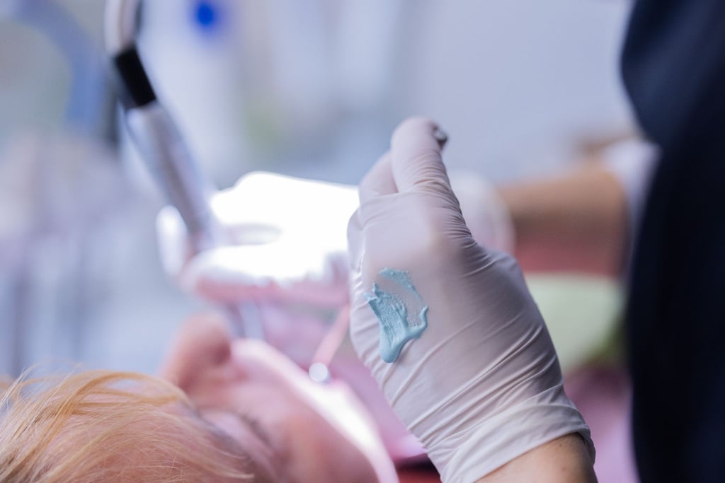 Eine Zahnarzthelferin führt an einer Patientin eine Zahnreinigung durch.