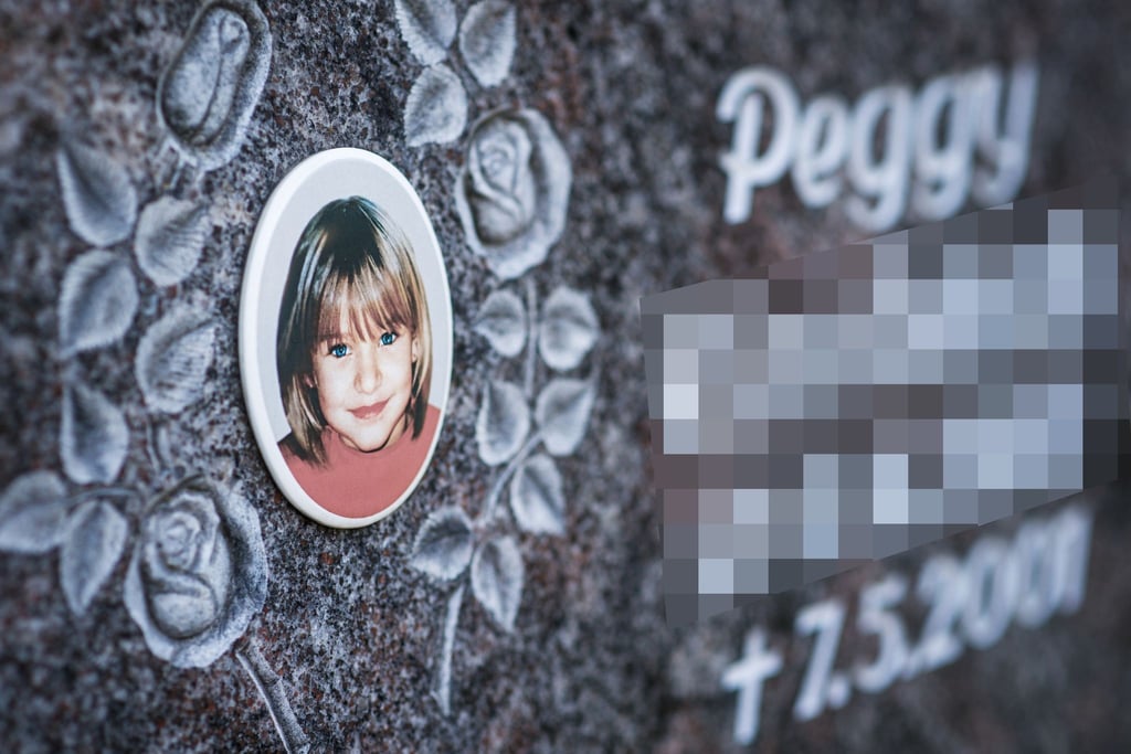 Ein Gedenkstein mit dem Porträt des Mädchens Peggy auf einem Friedhof.