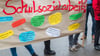 Teilnehmer halten ein Plakat mit der Aufschrift „Schulsozialarbeit“ hoch.