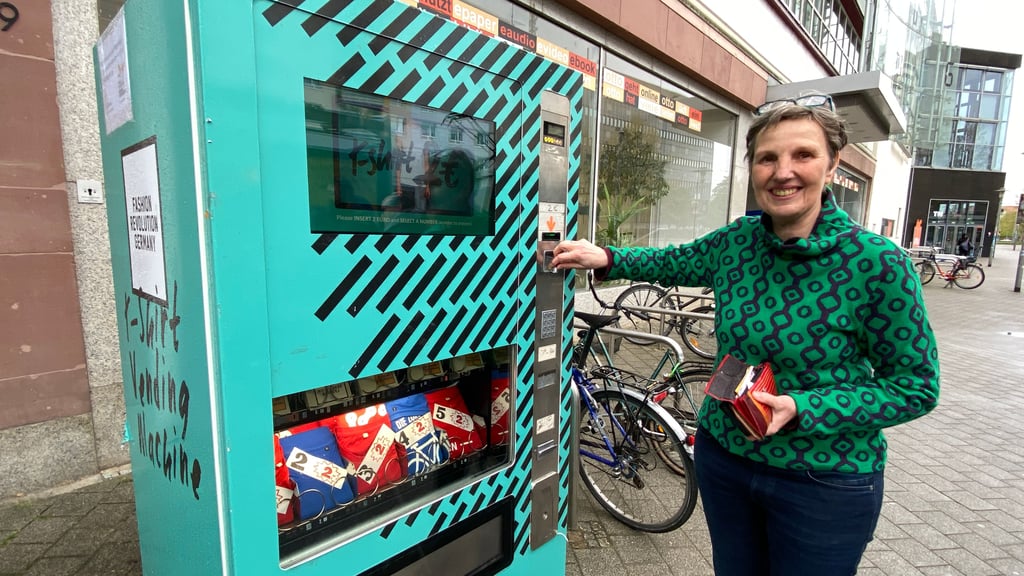 Maria Faber von der Diözesanstelle Weltkirche testet den T-Shirt-Automaten, der während der Fashion Revolution Week bis zum 28. April 2024 vor der Stadtbibliothek in Magdeburg steht.