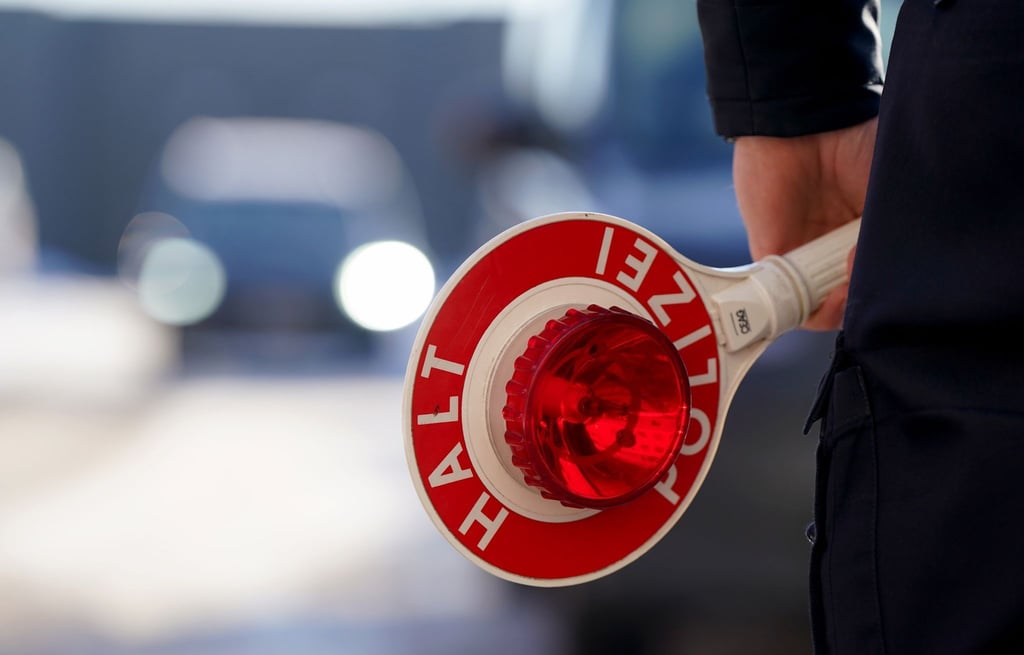 Ein Polizist hält eine Anhaltekelle in der Hand.