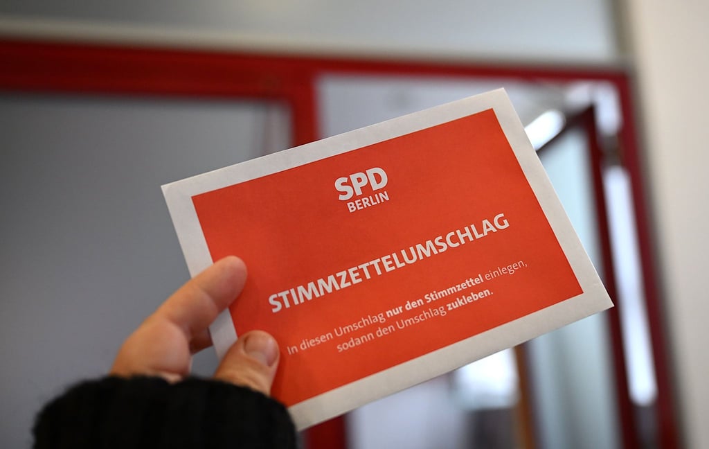 Ein Mann hält einen Stimmzettelumschlag in der Hand.