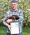 Tino Petrik ist jetzt Meister der Kaninchenzucht in Sachsen-Anhalt. Er zeigt die Urkunde und ein Tier der Rasse Thüringer (gemsfarben).  