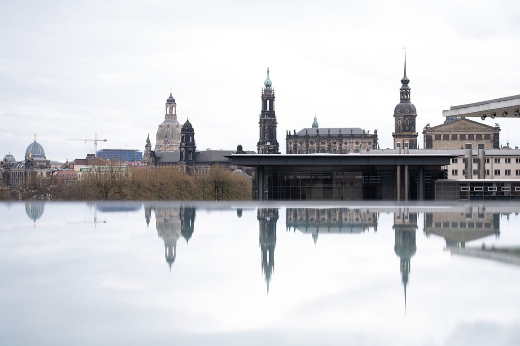 Die Kulisse der Dresdner Altstadt spiegelt sich in einer mit Regenwasser bedeckten Scheibe.
