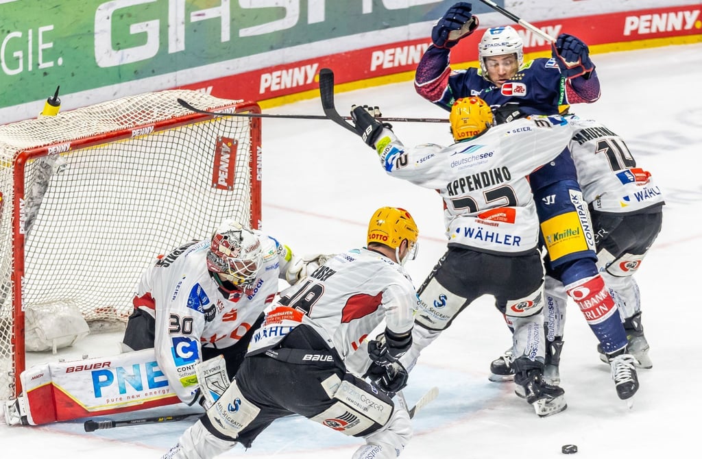 Ross Mauermann (r) und Nicolas Appendino (3.v.r) von Pinguins Bremerhaven verteidigen das Tor.