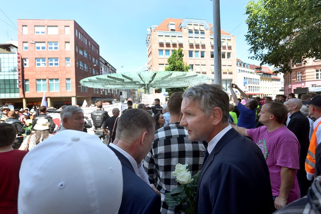 Björn Höcke steht am 25. Juni 2023 mit AfD-Sympathisanten vor Gegendemonstranten nahe einer Gedenkstele.