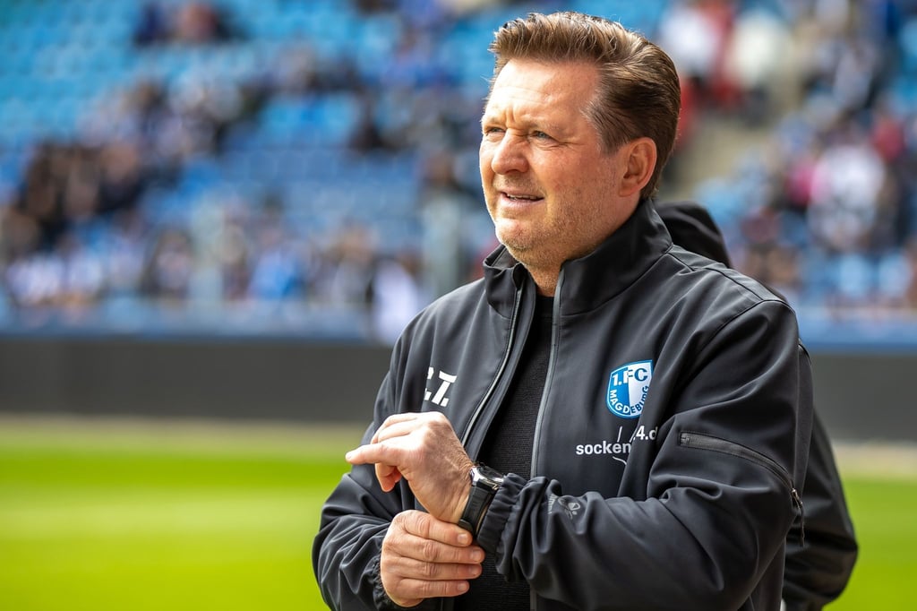 Trainer Christian Titz von 1. FC Magdeburg steht lächelnd am Spielfeldrand.