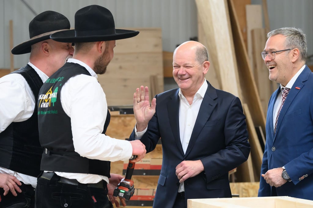 Bundeskanzler Olaf Scholz (SPD, 3.v.l.) scherzt bei seinem Besuch in einem Dresdner Handwerksbetrieb im Holzbau mit den Zimmermeistern Ralf Lepski (l), Felix Lepski (2.v.l.) und Jörg Dittrich (r), dem Präsidenten des Zentralverbandes des Deutschen Handwerks (ZDH) und Präsident der Handwerkskammer Dresden.