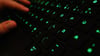 Ein Mann tippt auf einer beleuchteten Tastatur.