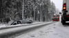 Ein Auto steht nach einem Unfall neben der schneebedeckten Fahrbahn im Graben, während ein Räumfahrzeug angefahren kommt.