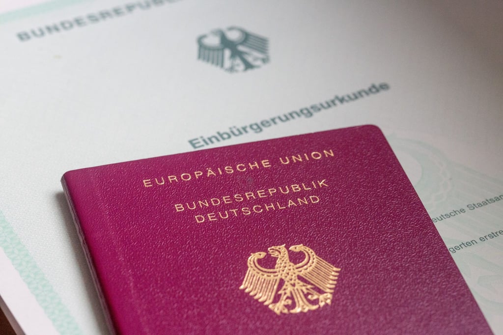 Eine Einbürgerungsurkunde der Bundesrepublik Deutschland und ein deutscher Reisepass liegen auf einem Tisch.