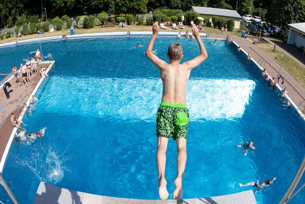 Ein Junge springt vom 5-Meter-Turm ins Wasser.