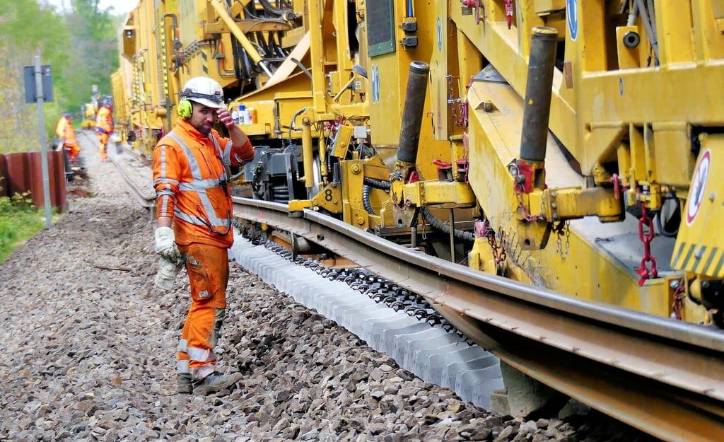 20 Kollegen arbeiten auf oder neben dem Schienenzug. Den Wechsel der Schienen (oben die alte) und Schwellen vollsieht der Zug automatisch.