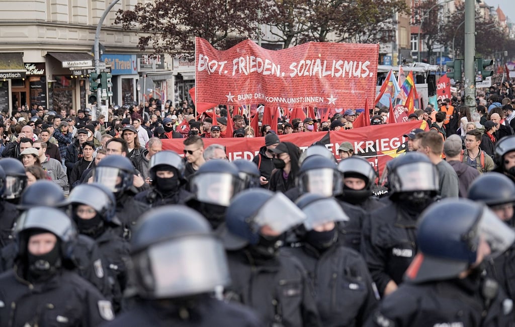 Ein Demonstrationszug zieht unter Polizeibegleitung mit Transparenten durch die Stadt.