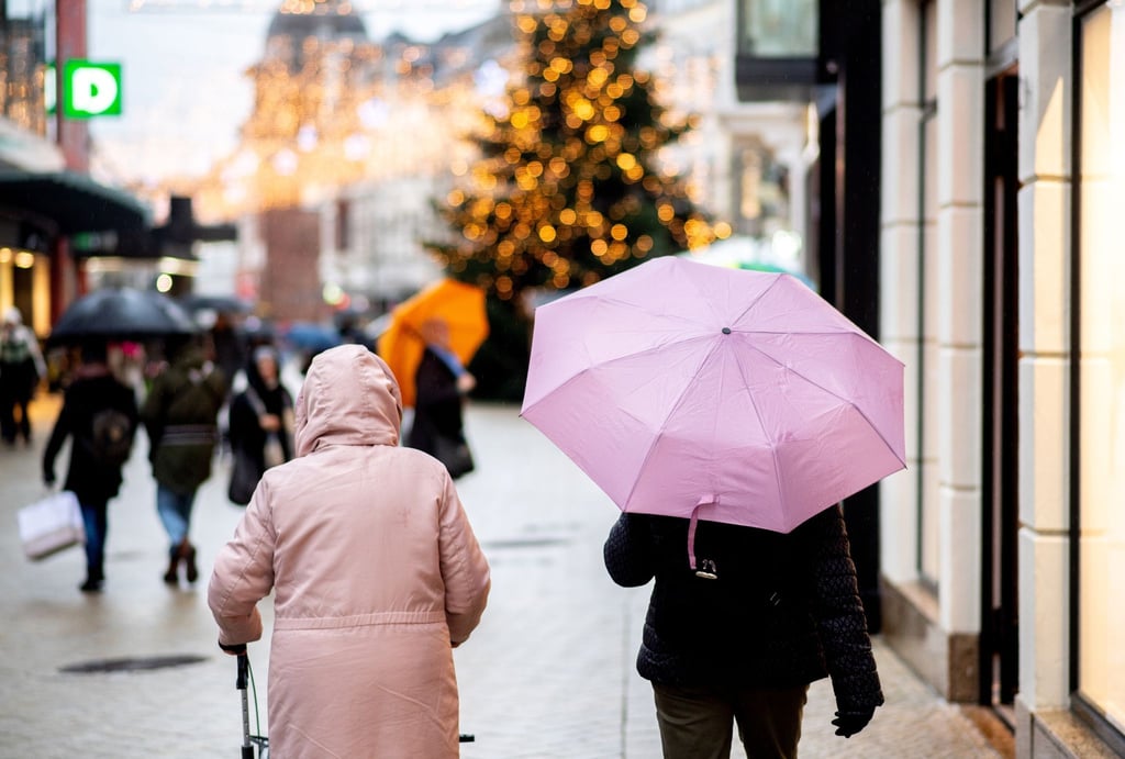 Menschen gehen bei regnerischem Wetter mit Regenschirmen durch die Innenstadt.
