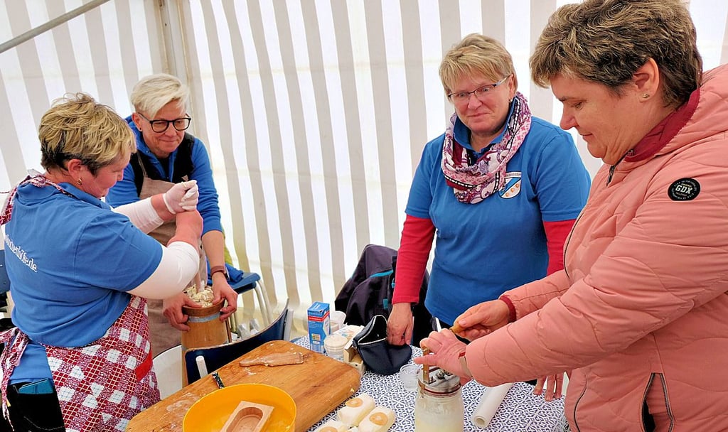 Mit viel Muskelkraft stellen mehrere Mitgliederinnen des Heimatvereins an einem Stand im Festzelt Butter her.