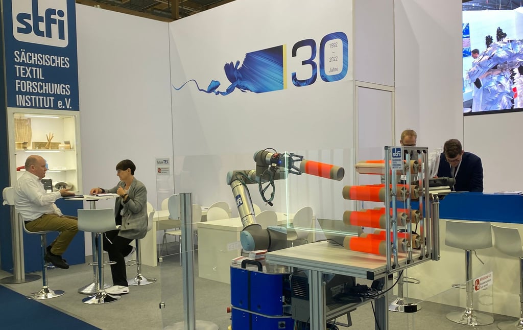 Ein mobiles Robotersystem zur automatisierten Bestückung eines Spulengatters auf der Messe Techtextil.