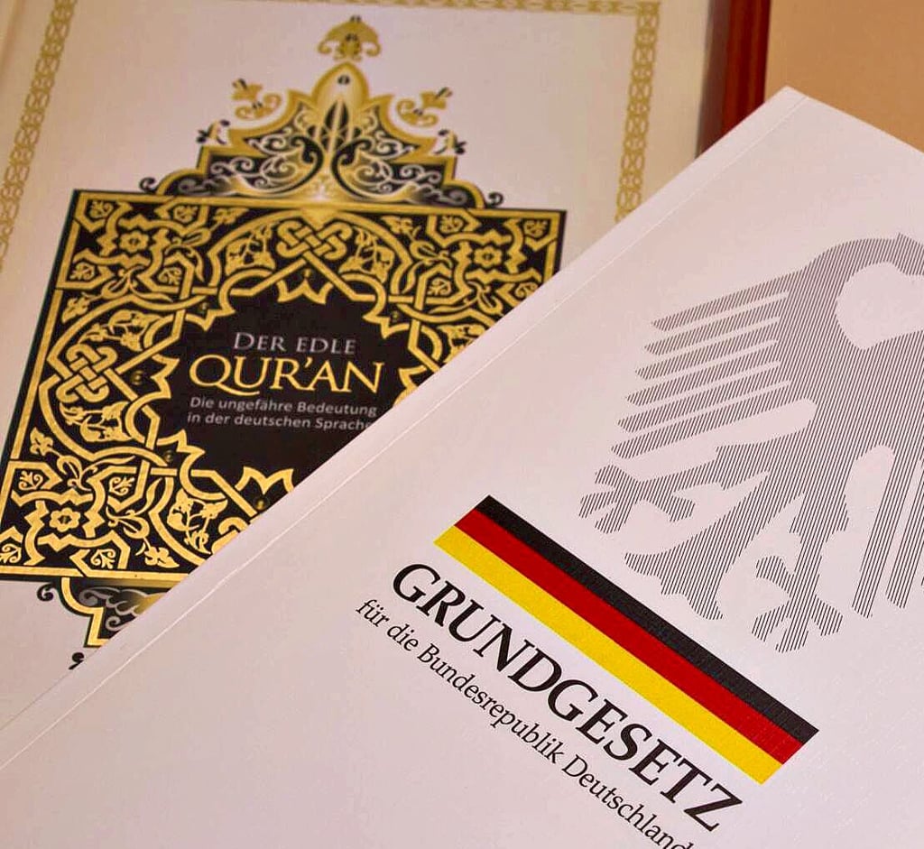 Ein Koran und das Grundgesetz liegen auf einem Tisch.
