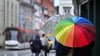 Fußgänger laufen mit Regenschirmen durch die Marktstraße.