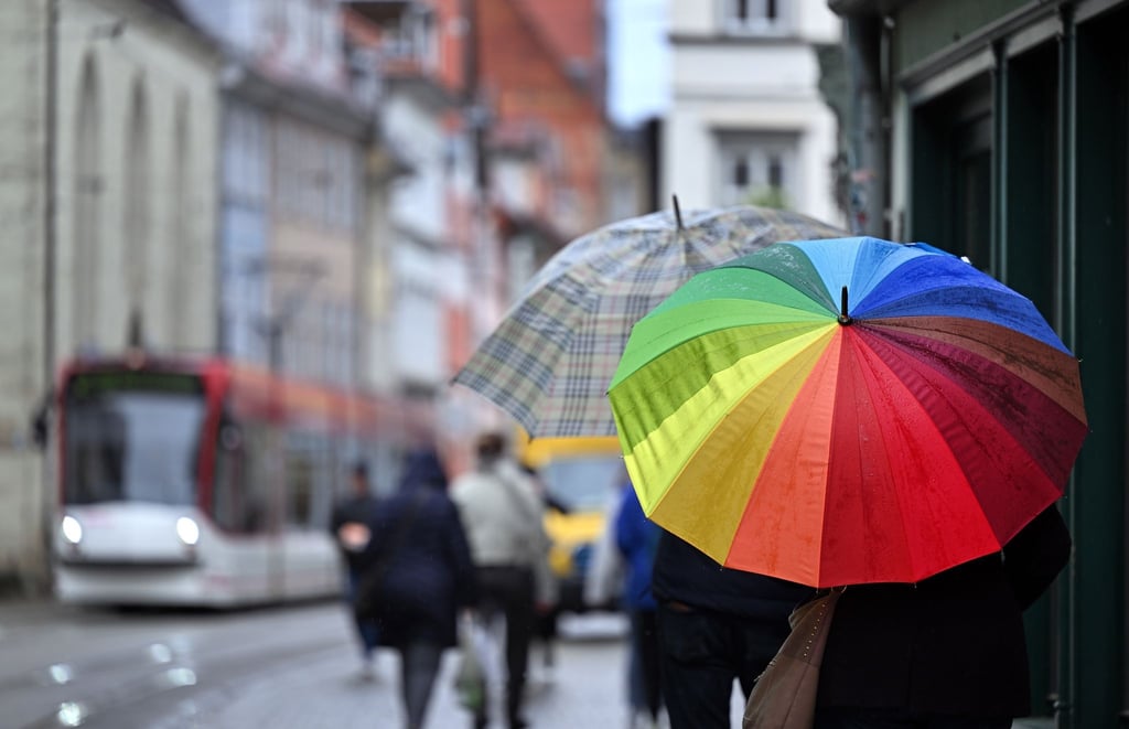 Fußgänger laufen mit Regenschirmen durch die Marktstraße.