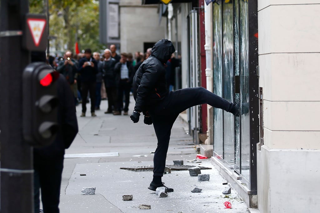 Ein Demonstrant tritt in Paris (Frankreich) bei einem Protest gegen ein Fenster einer Bank.