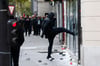 Ein Demonstrant tritt in Paris (Frankreich) bei einem Protest  gegen ein Fenster einer Bank. 