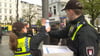 Mitarbeiter der Polizei befestigen einen Zettel für eine Zeugensuche an einem Laternenpfosten.