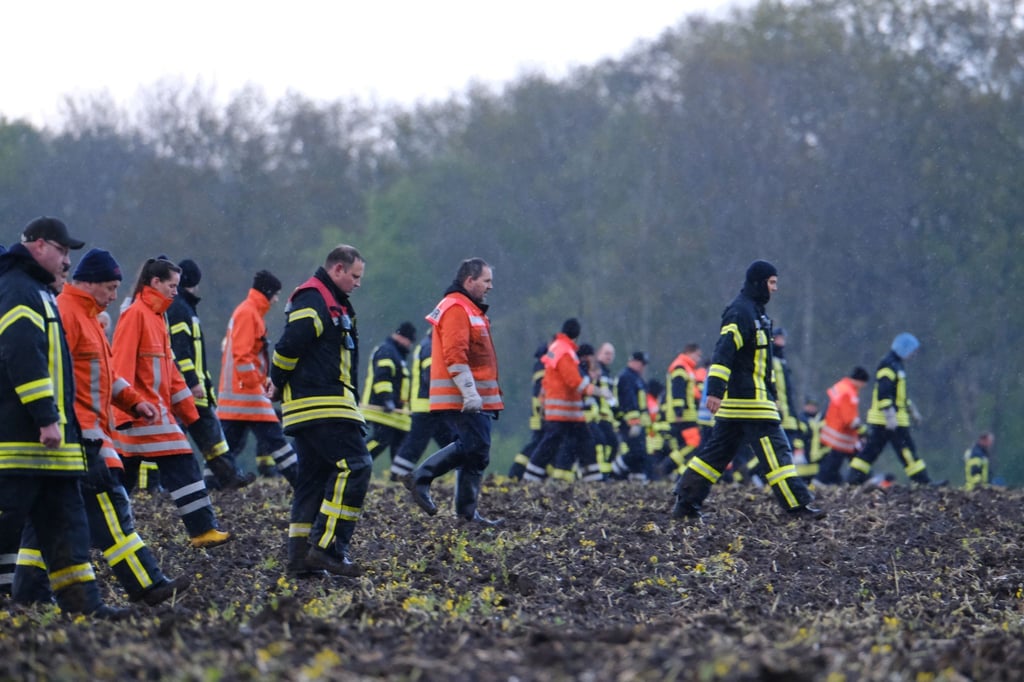 Feuerwehrleute laufen über einen Acker bei Bremervörde.