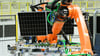 Ein Solarmodul wird mit einem Roboter zum nächsten Arbeitsgang transportiert.