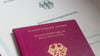 Eine Einbürgerungsurkunde der Bundesrepublik Deutschland und ein deutscher Reisepass liegen auf einem Tisch.